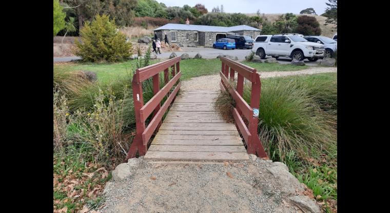 Medium bridge, wide enough for two people, small lip transitioning from gravel.